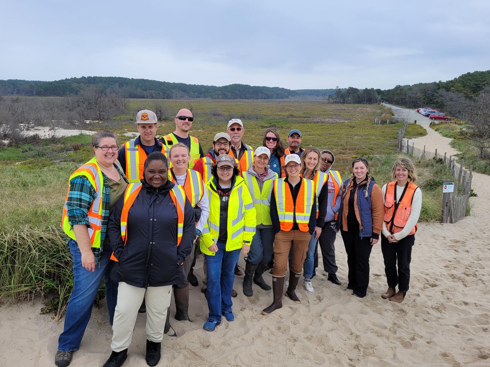 DER staff wearing high visibility vests and standing in front of a marsh.