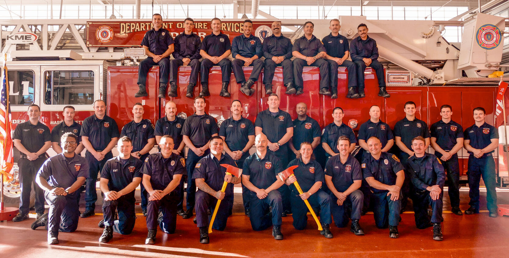 Photo of 30 firefighters on and around a ladder truck