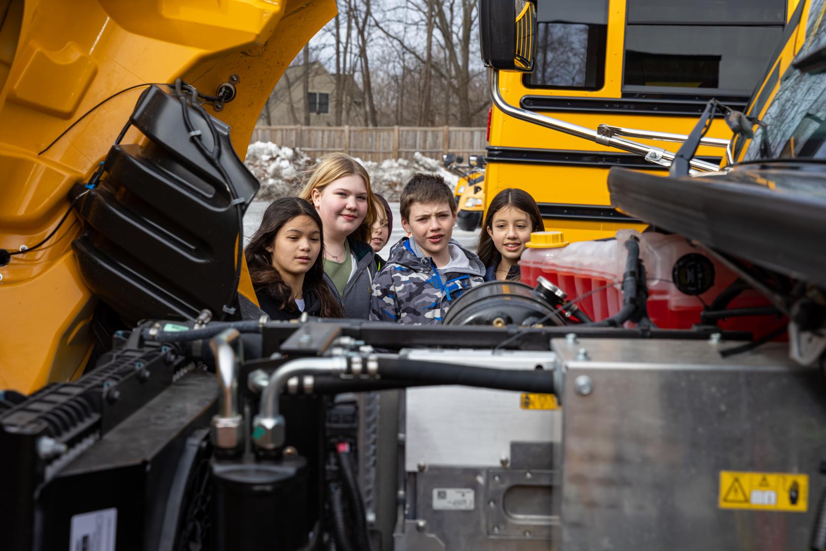 Children look at an electric school bus engine from the Lt. Governor Driscoll tour of clean energy and climate mitigation projects at Beverly Middle School