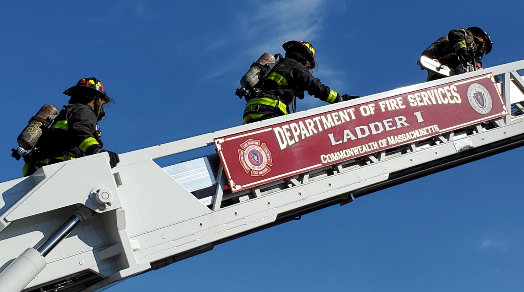 Photo of three firefighters climbing an aerial ladder