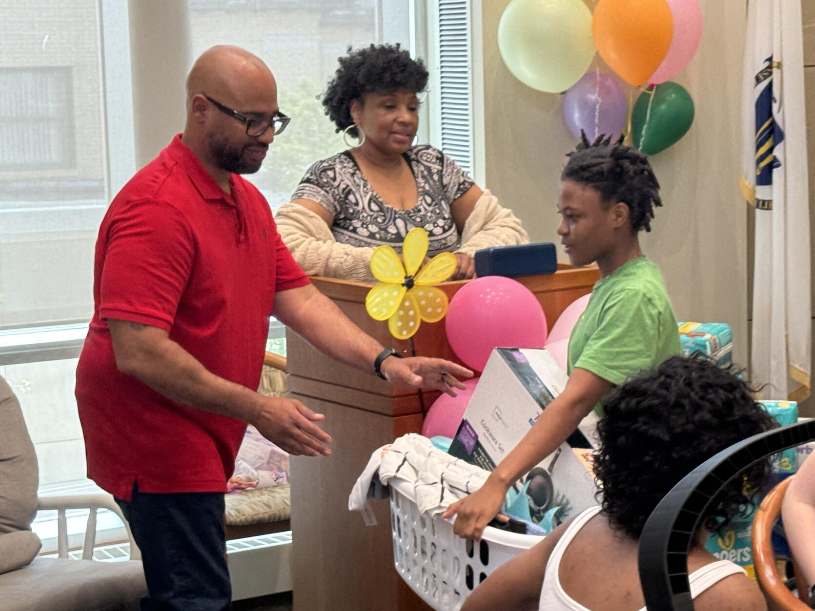 Chief Probation Officer Mike Branch hands Ruth House resident Jasmine a basket filled with housewares and items for her baby.