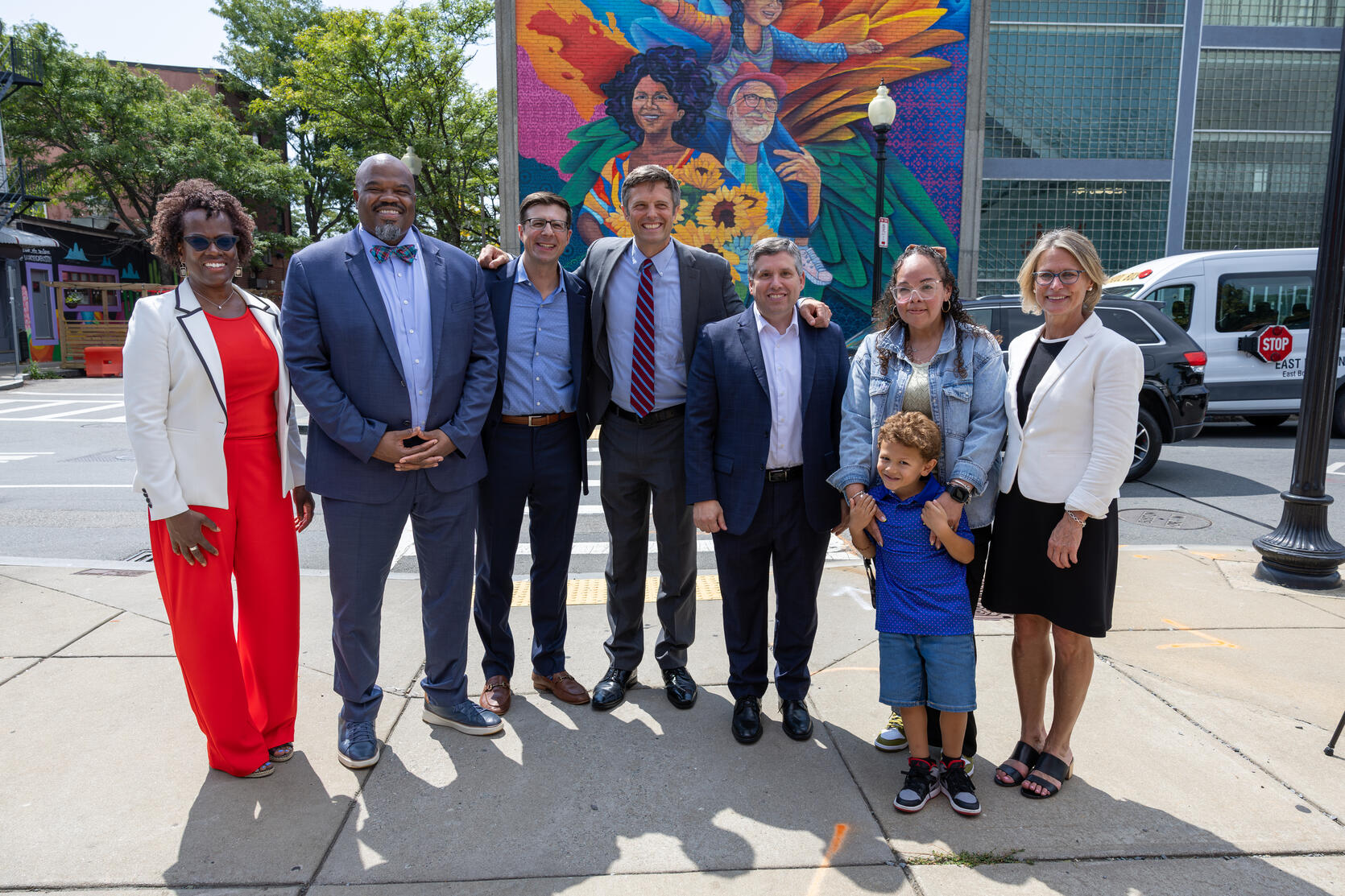 Secretary Tutwiler, Commissioner Kershaw, and local legislators take a group photo with East Boston Social Centers outside their early education and care space.
