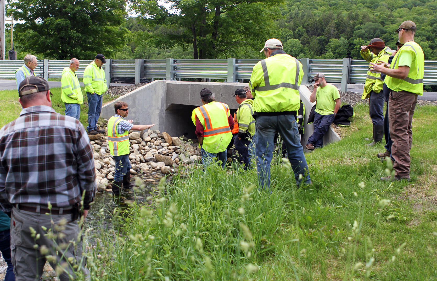 Several people in high visibility vests standing around a new culvert during a training.