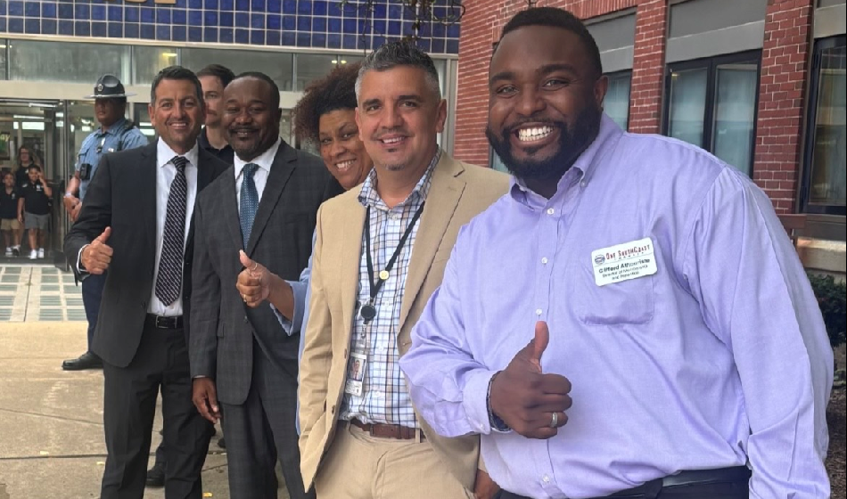 A group of people pose with their thumbs up.