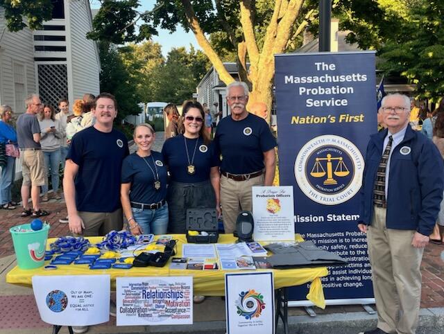 A group poses for a picture from behind a table with informational material.