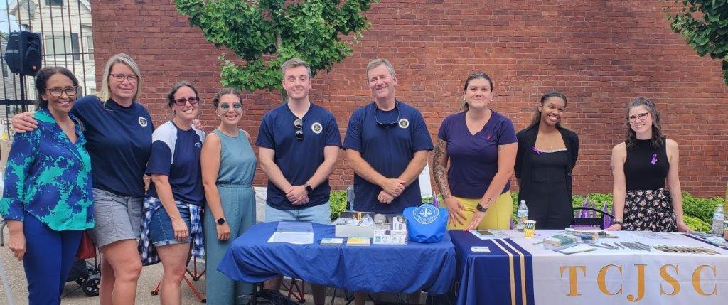A group poses for a picture from behind a folding table.