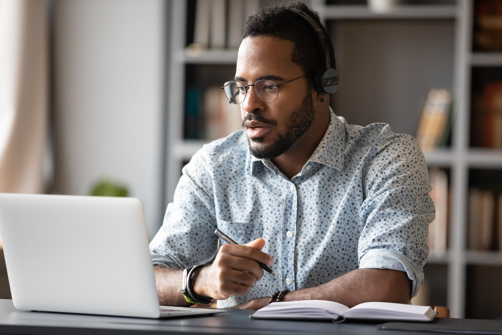 Black, middle-aged, man in a home office looking at laptop while working.