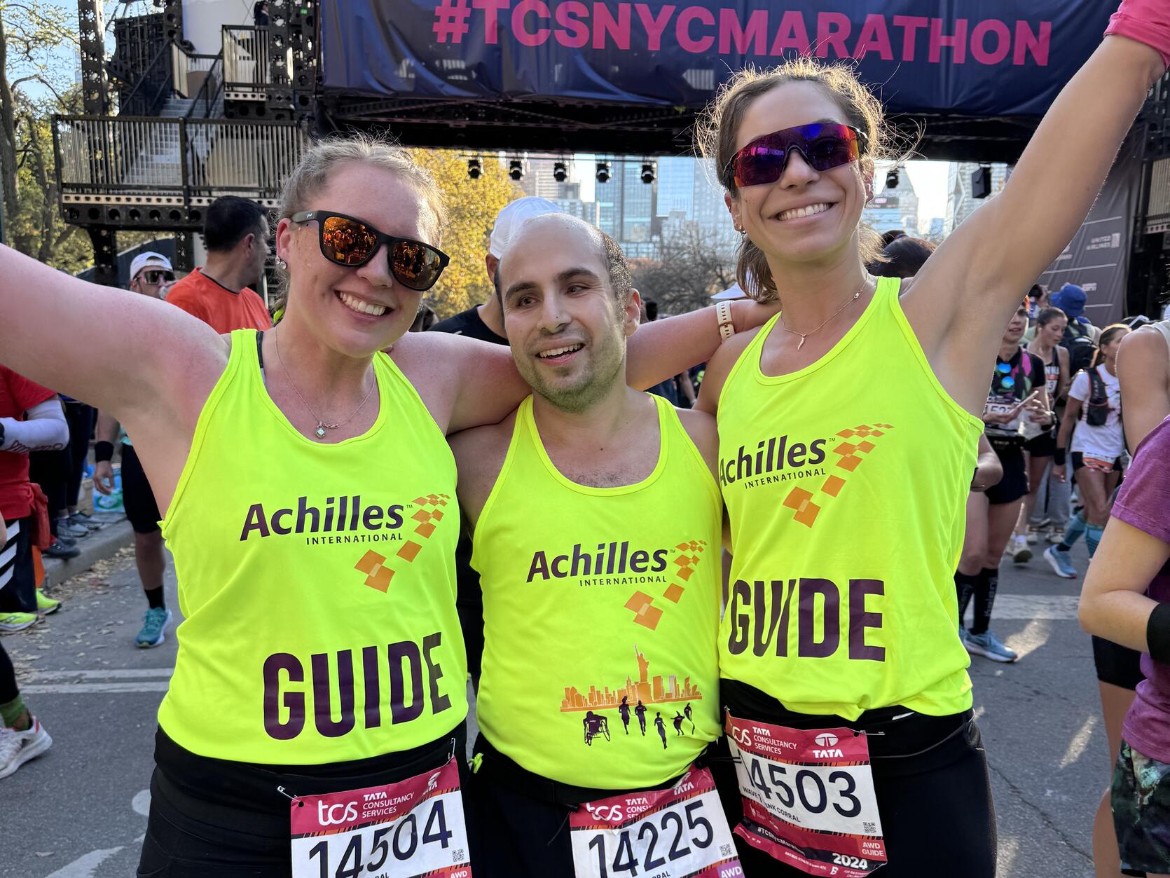 Three people pose at the finish line together after finishing the NYC Marathon.