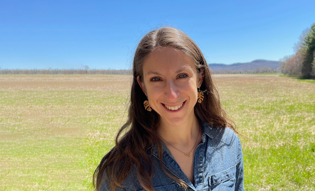 Photo of woman smiling with background of blue sky and green field