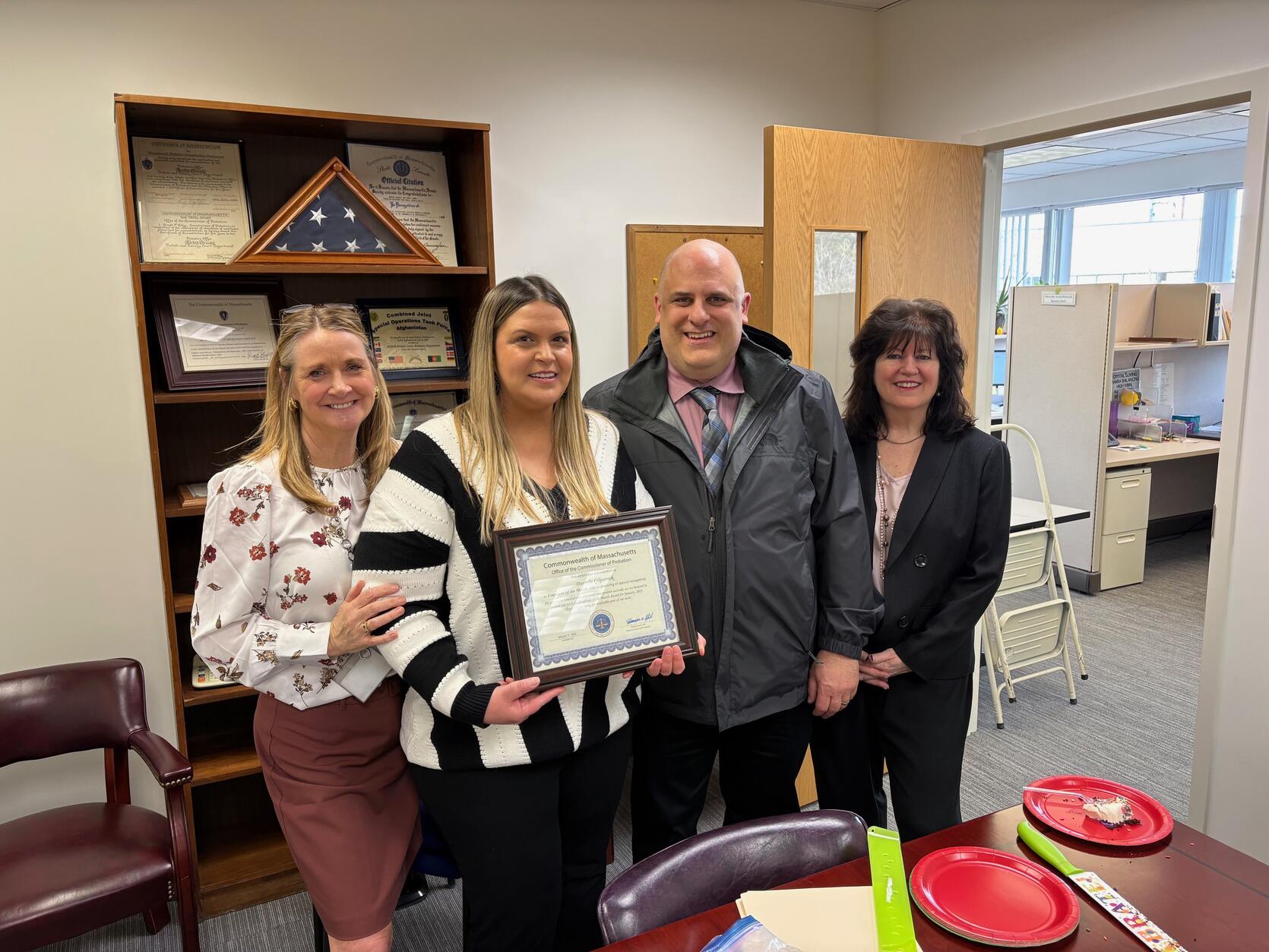 Danielle Gilpatrick holds a certificate and poses with colleagues and her husband.