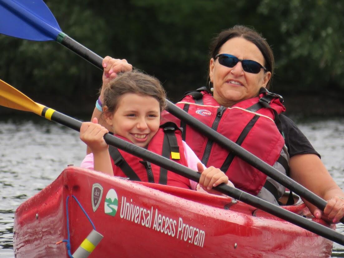 Two people are paddling in a tandem kayak on a pond. 