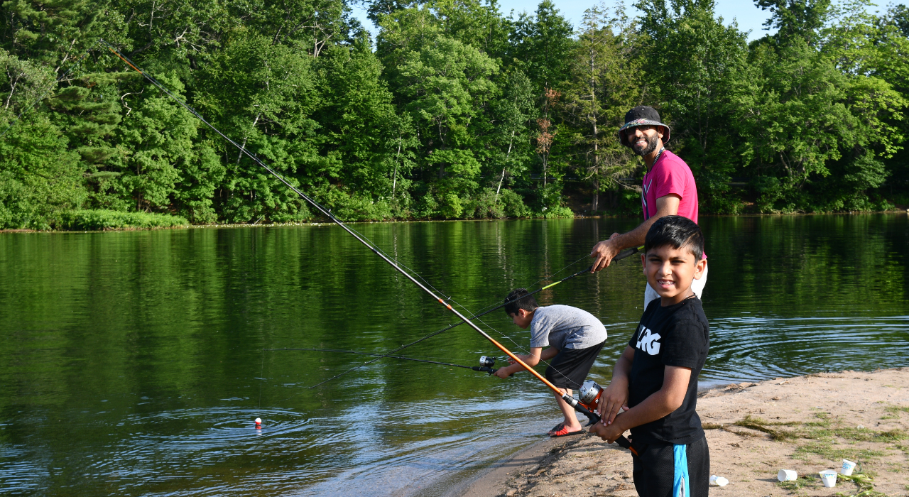 Photograph of two kids and an adult fishing at a pond