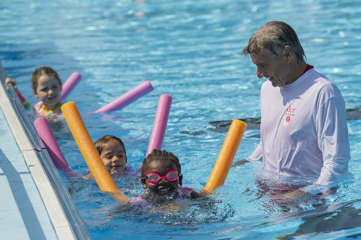 man and kids in pool