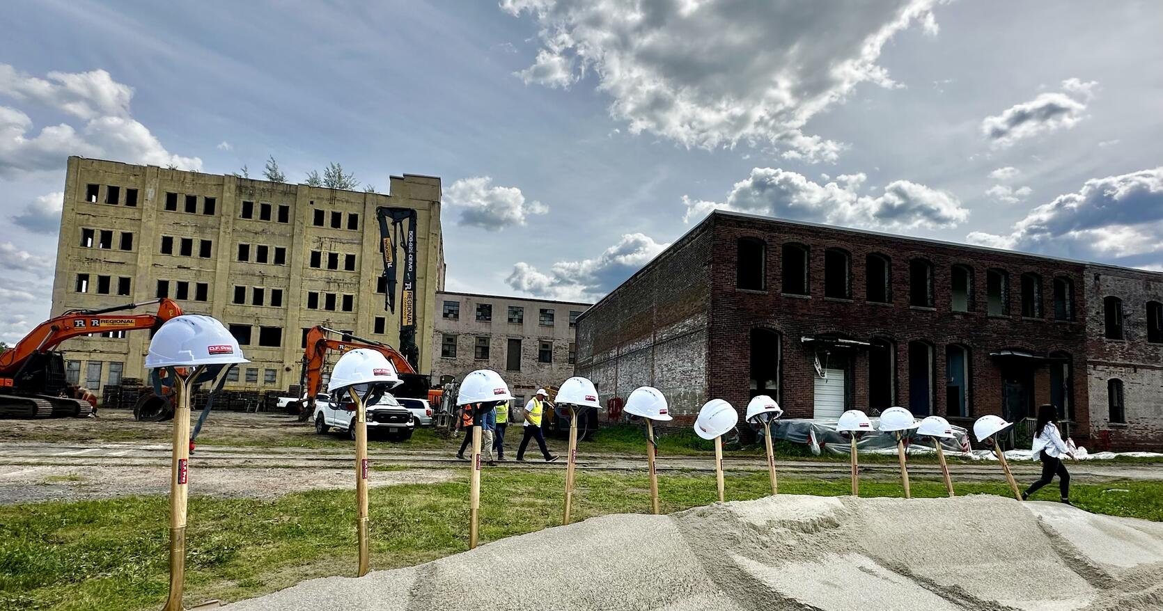 Hard hats and shovels in front of an old mill construction site