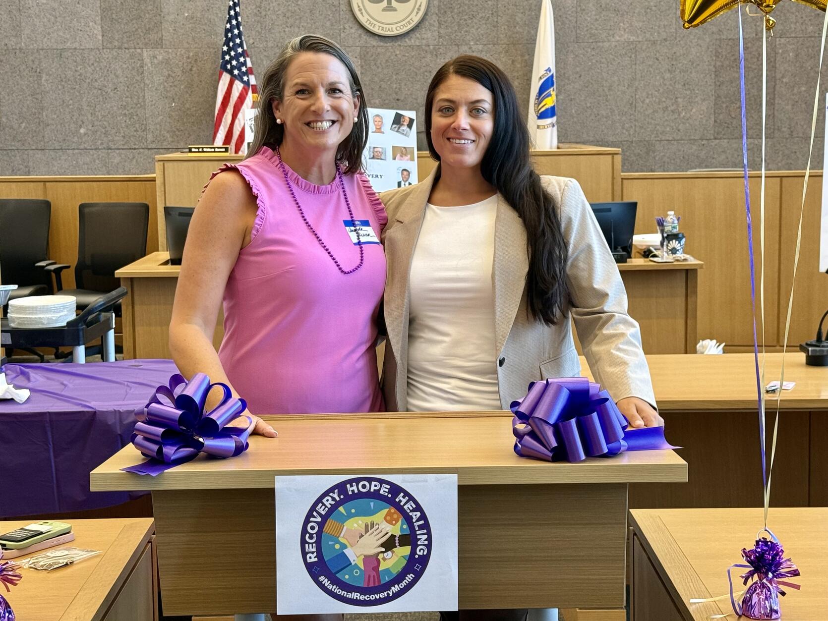 Two women pose together at a podium
