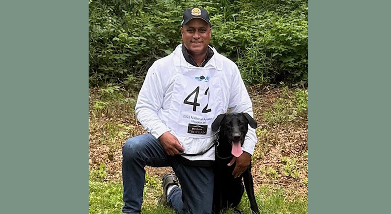 Malcolm Haith kneeling alongside black dog