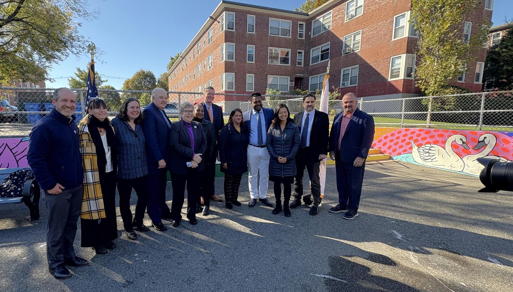 Officials gather for a photo at the site of the Faneuil Gardens public housing development