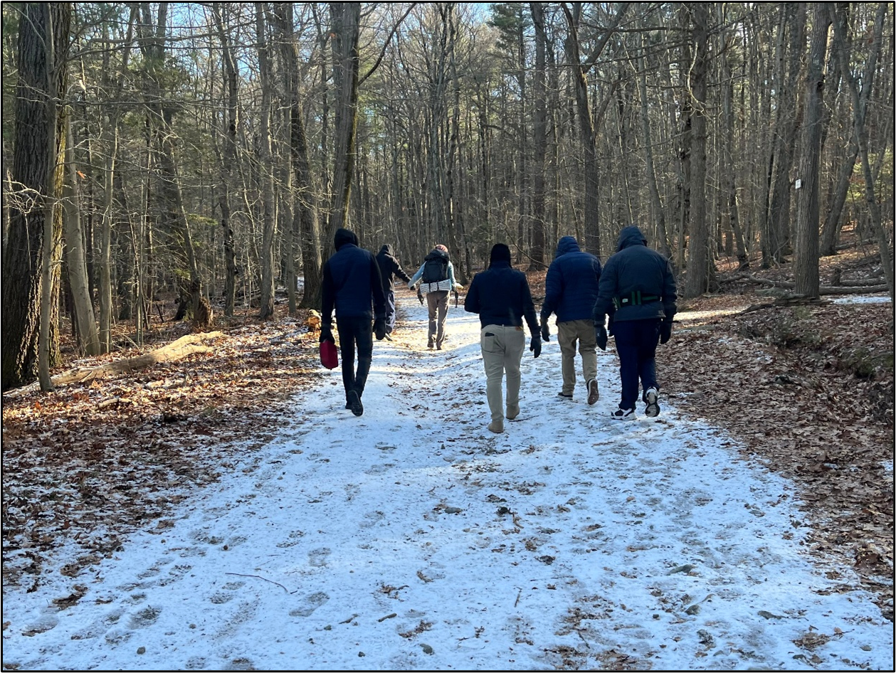A group of people are hiking on a snow covered trail in the woods.