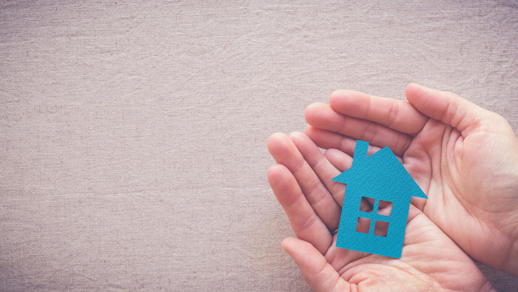 Illustration of a hand holding a paper cut out of a home.