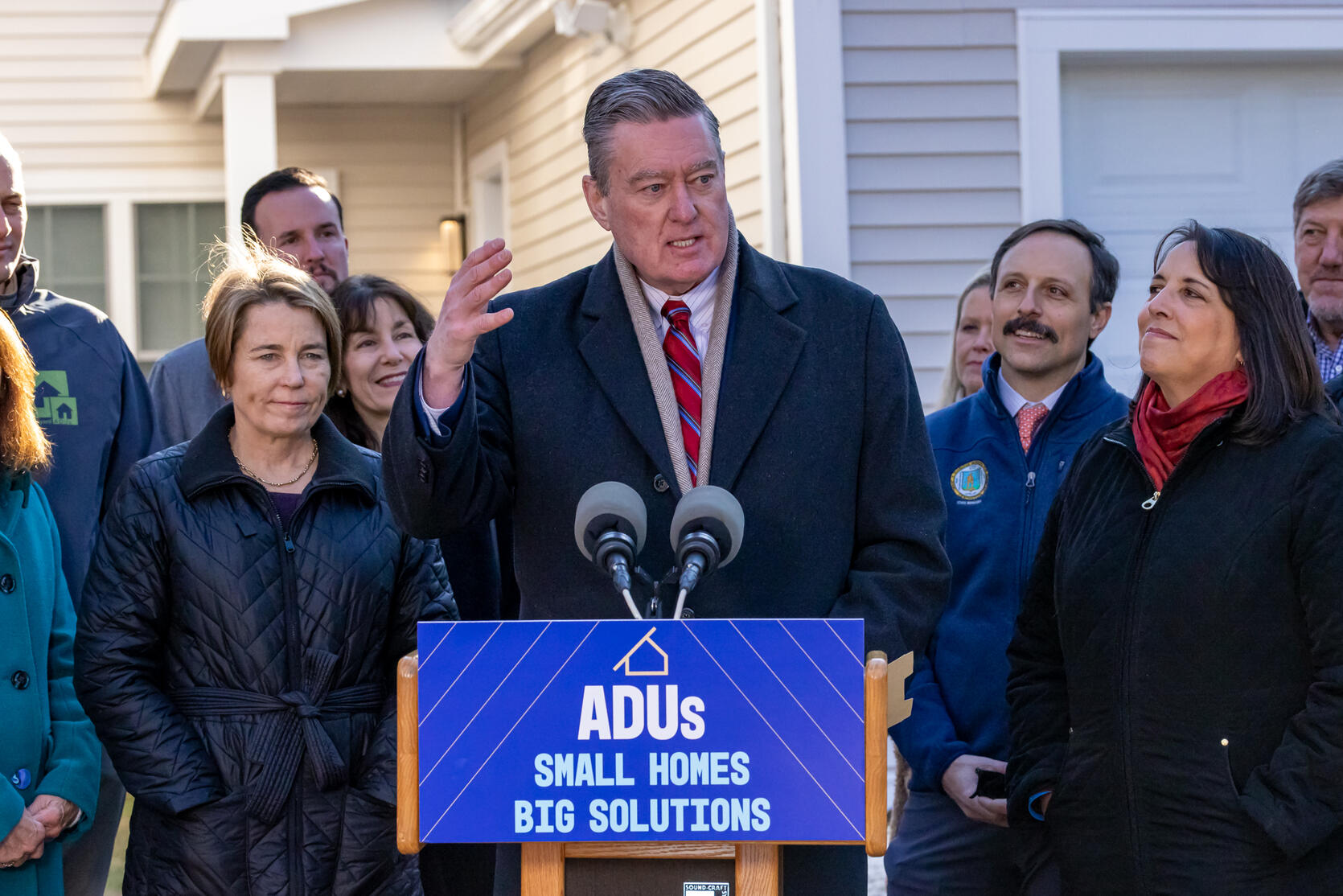 Executive Office of Housing and Livable Communities Secretary Ed Augustus speaks, flanked by Governor Maura Healey and Lieutenant Governor Kim Driscoll