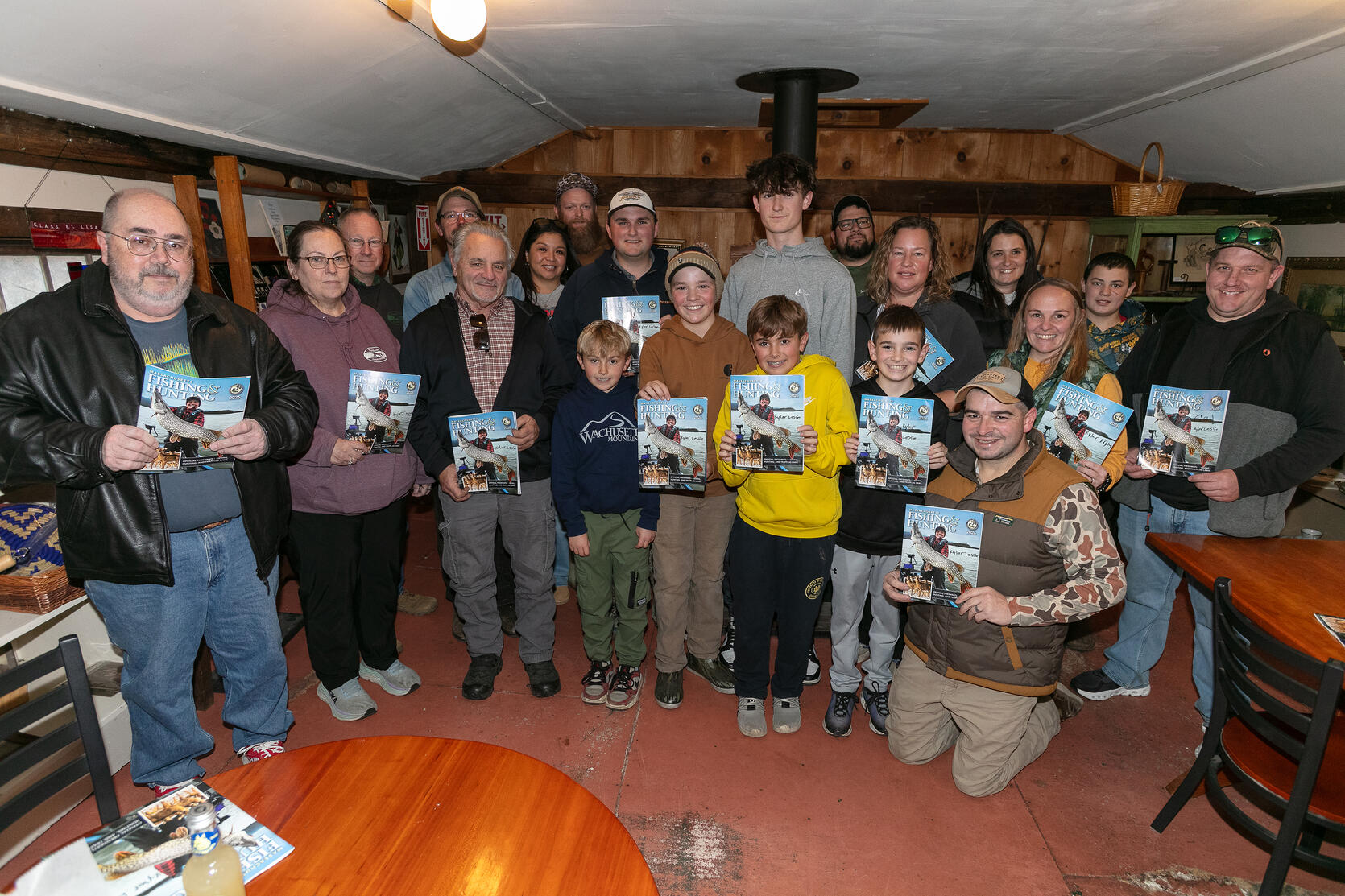family and friends gather to celebrate young angler on cover of the fishing and hunting guide