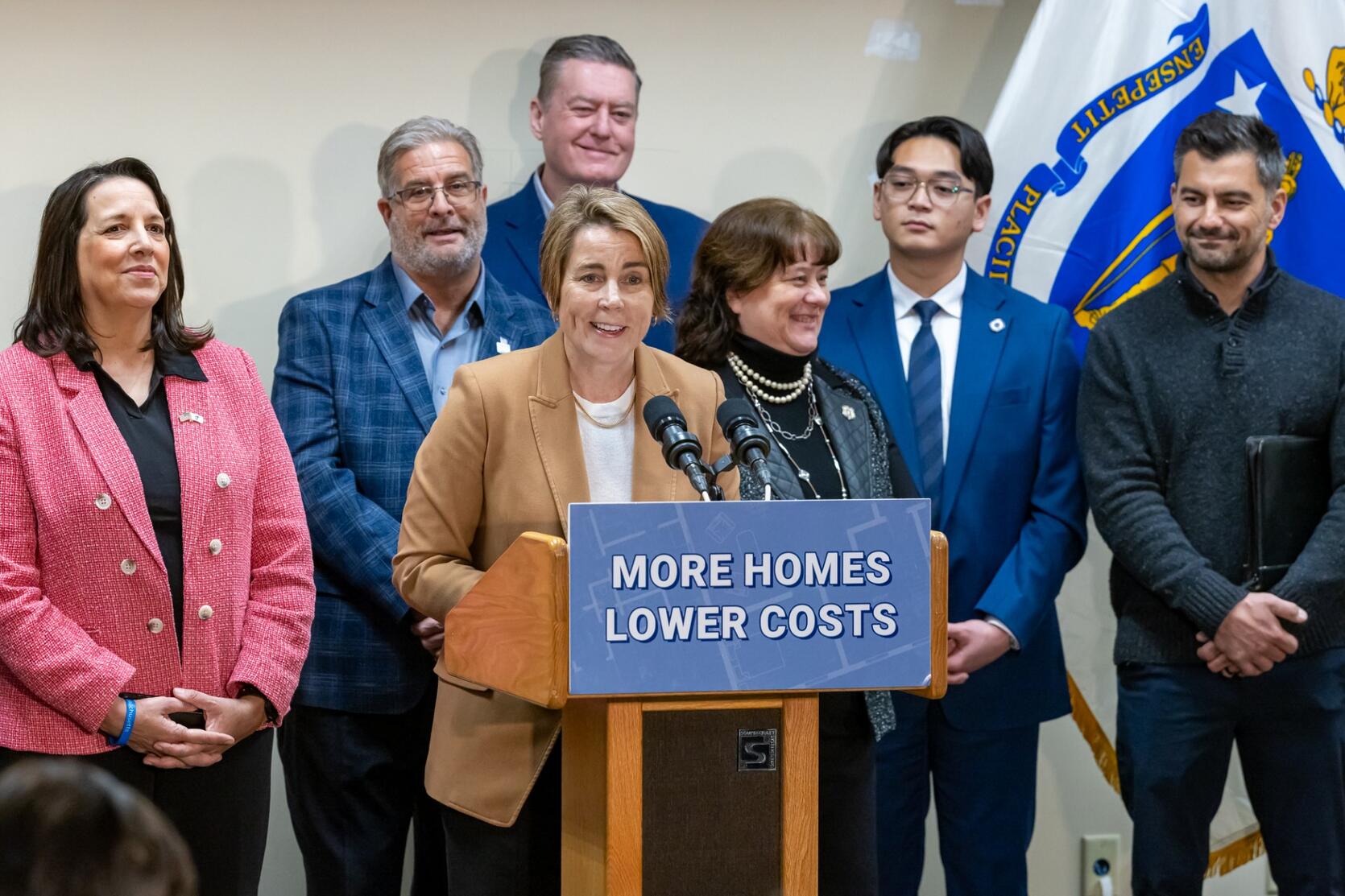 Governor Healey, Lieutenant Governor Driscoll, Secretary Augustus and others gather at a podium to announce the awards