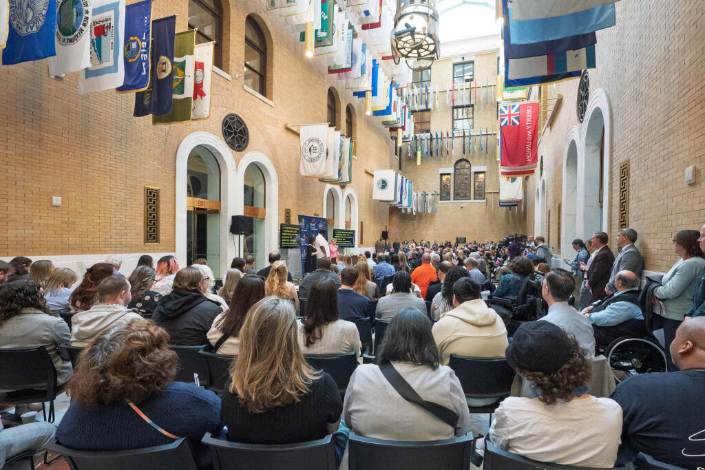 A crowd of people gathered in the State House's Great Hall of Flags.