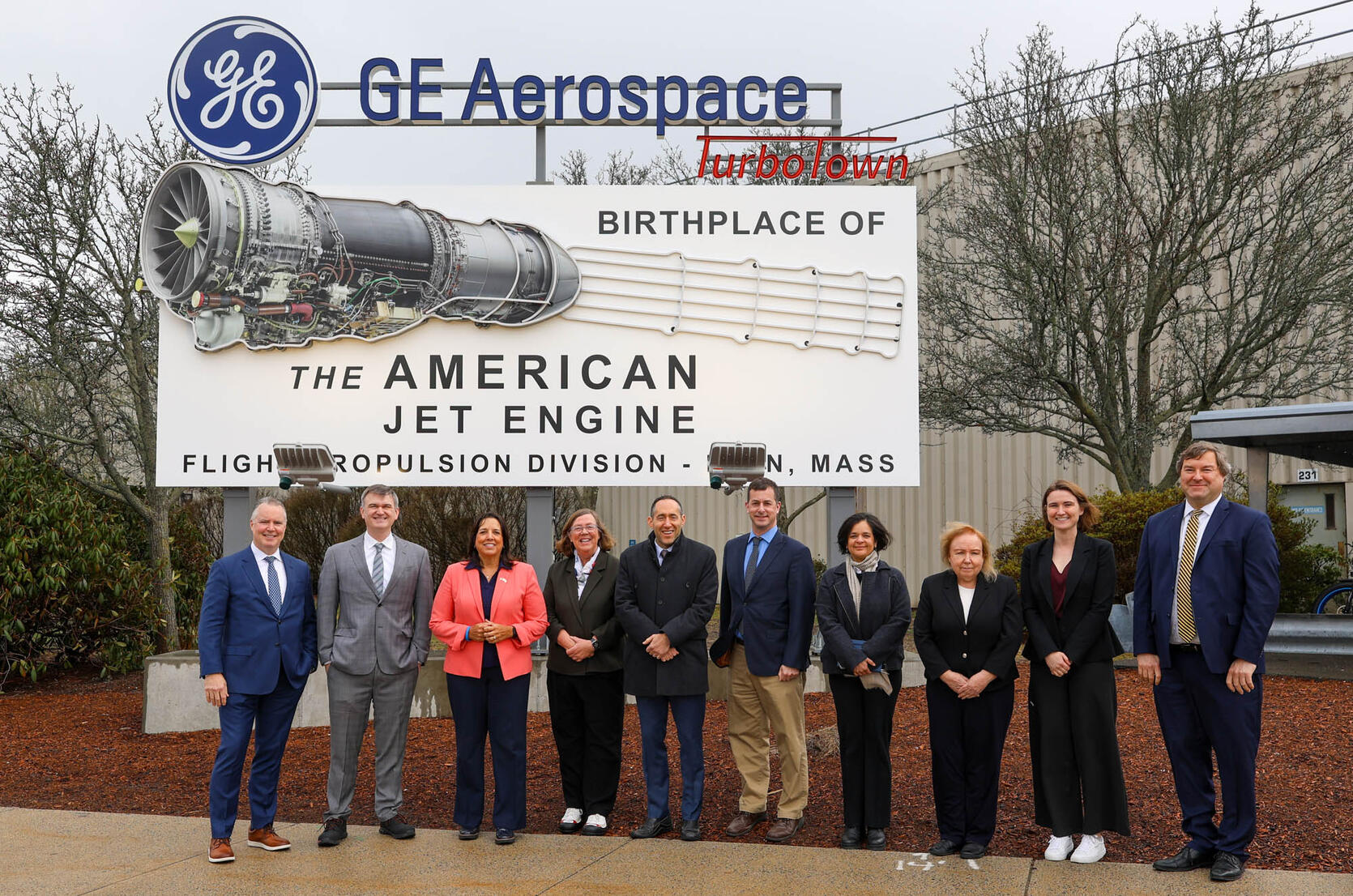 ten people in front of a ge aerospace sign outside