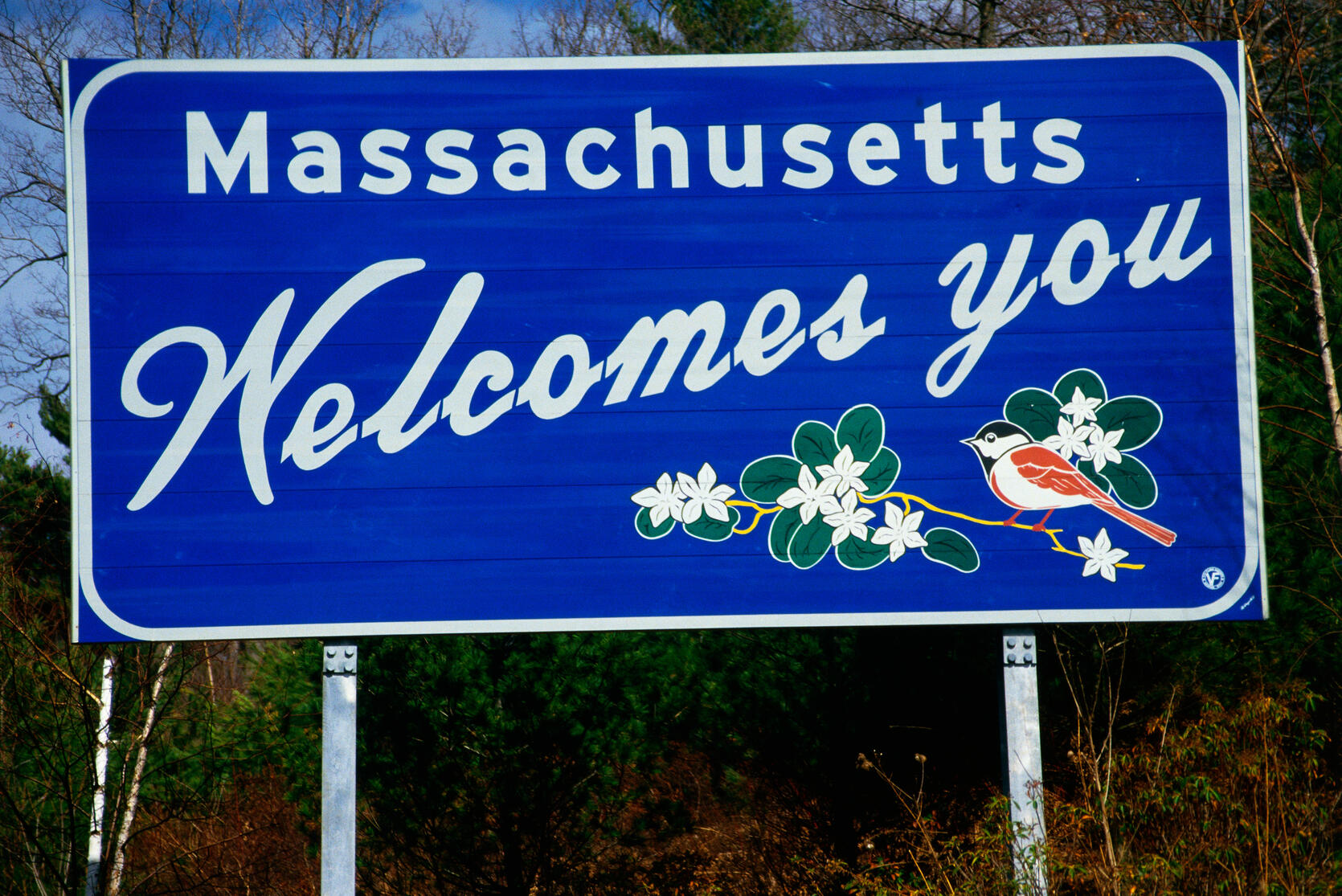 A Massachusetts welcomes you road sign with a chickadee on it