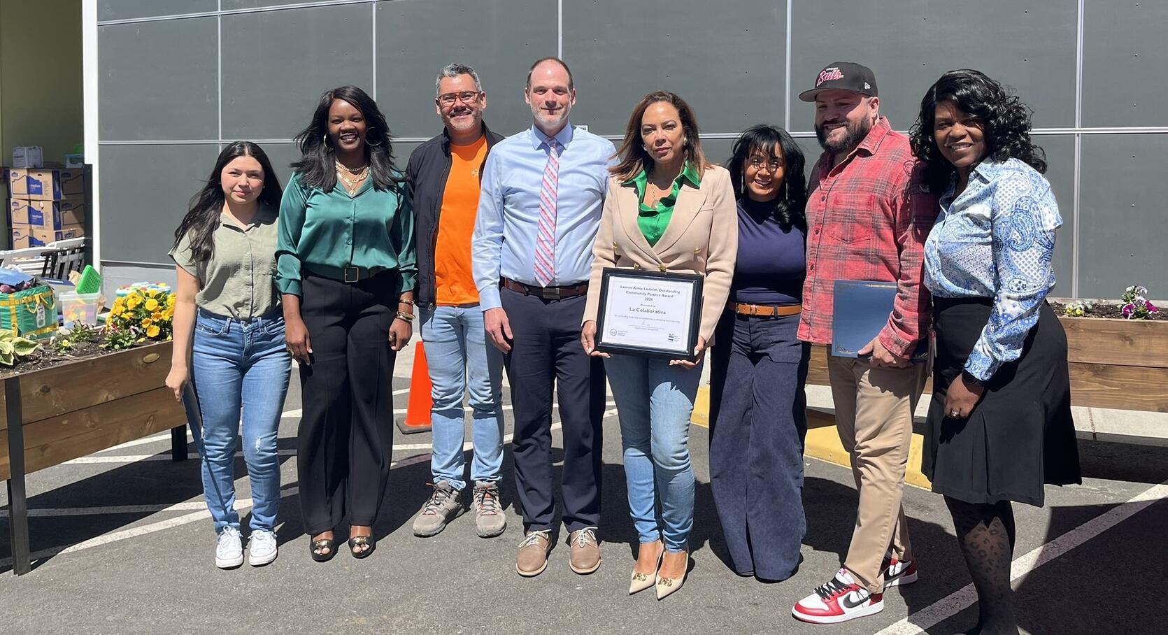 An outside shot of a group of people, including leaders from DTA and La Colaborativa pose for a photograph.