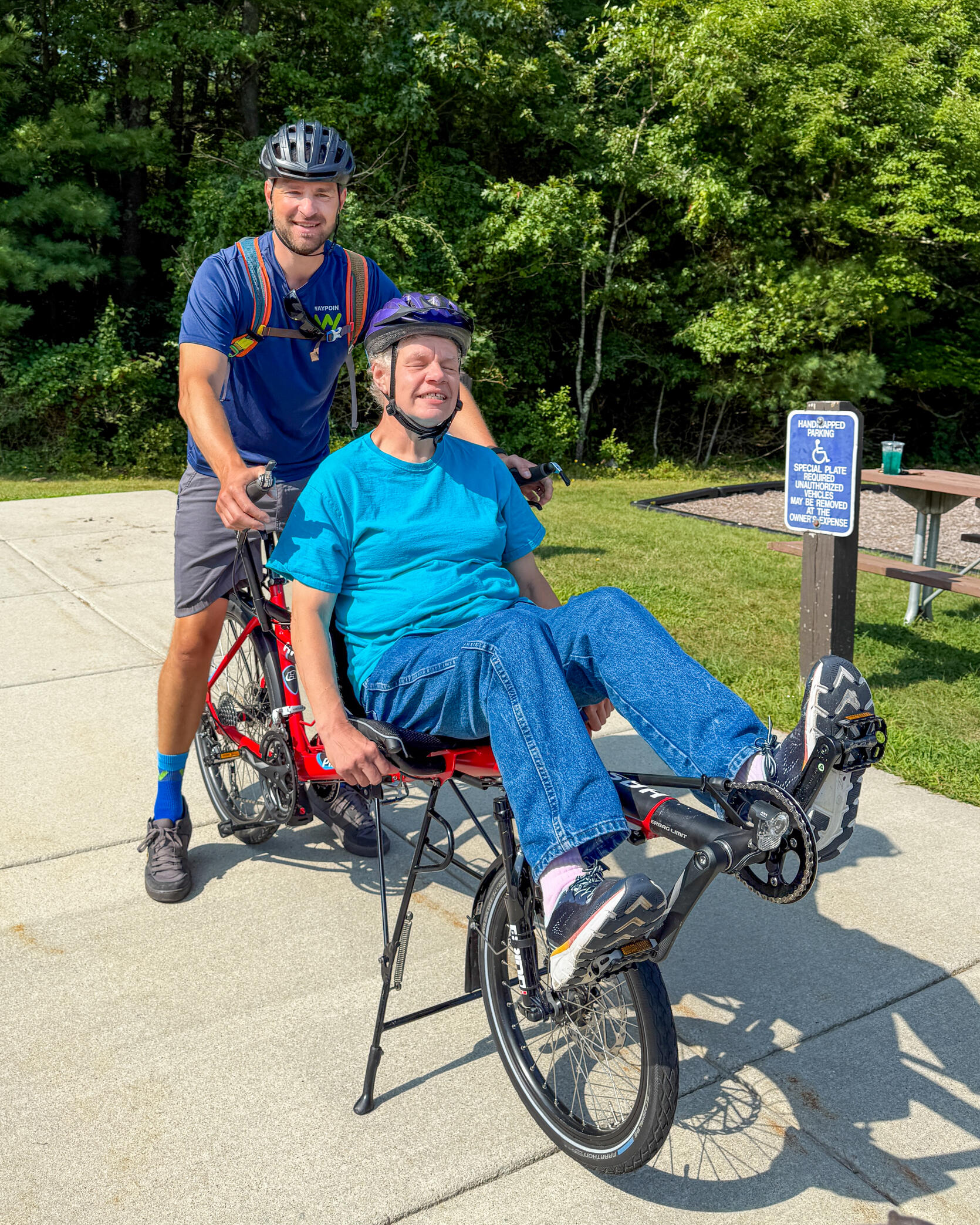 Two people riding a semi-recumbent tandem cycle smile while taking a break.  