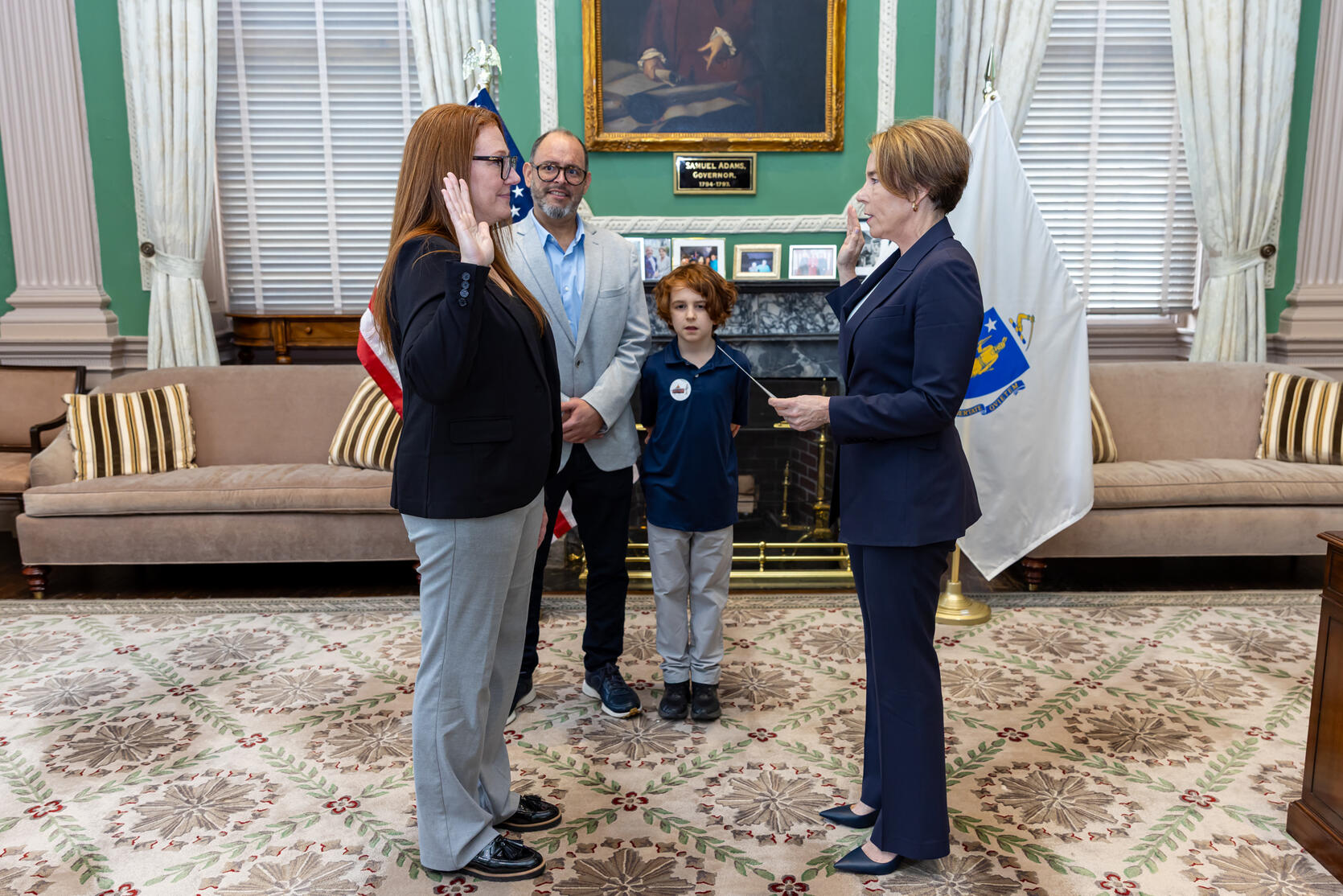 Commissioner Baily takes the oath of office at the state house with Governor Maura Healey. Her family watches in the background. 