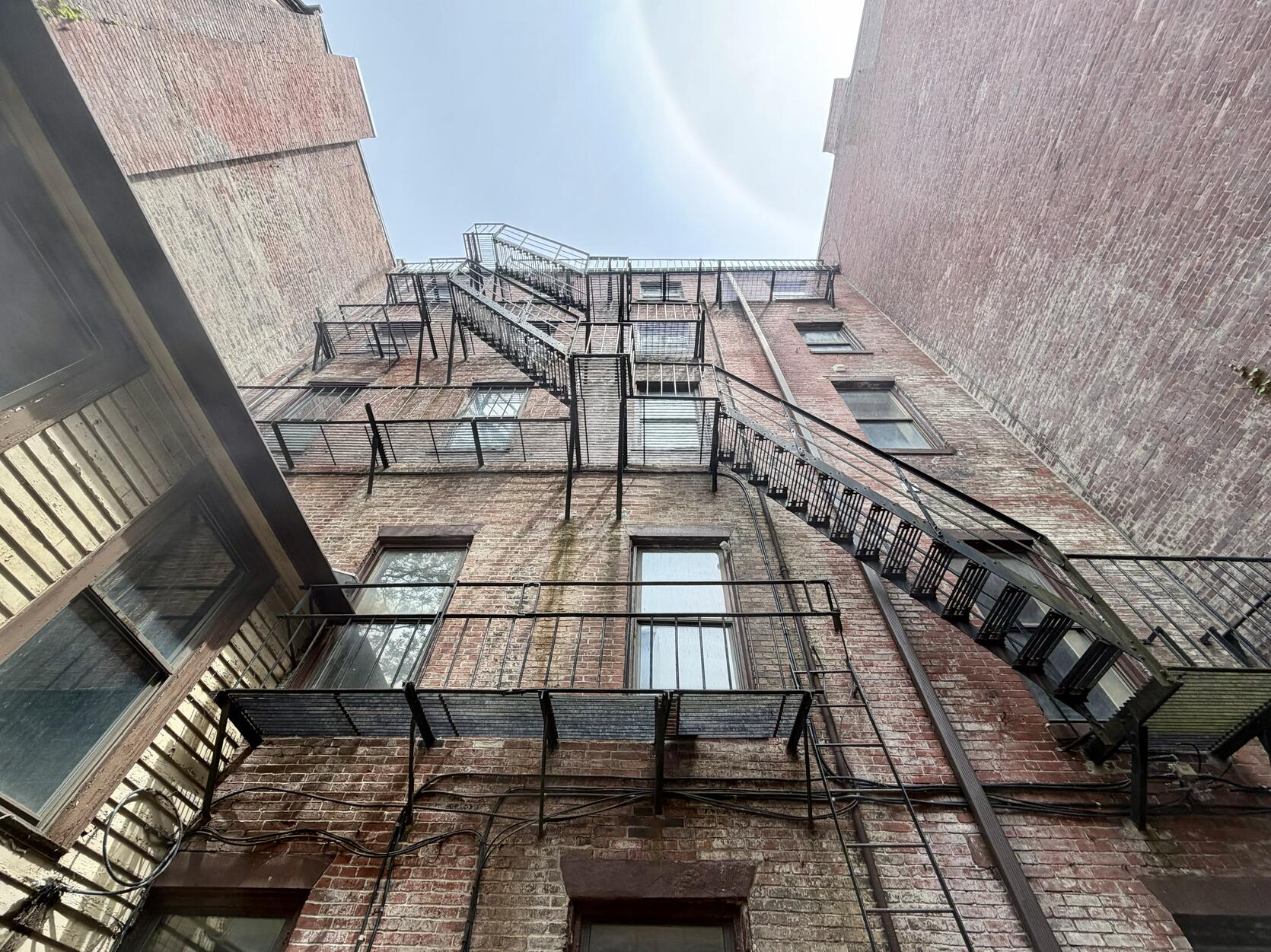 A metal fire escape zig-zags up the back of a tall brick building on Boston's Beacon Hill that is being turned into affordable homes