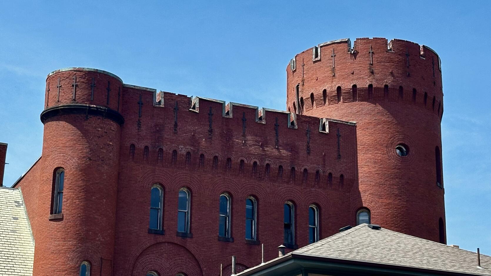 The turret of the Lynn Armory rises before a blue sky