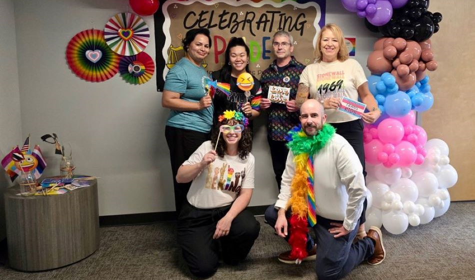 A group of 6 people pose in Pride attire.
