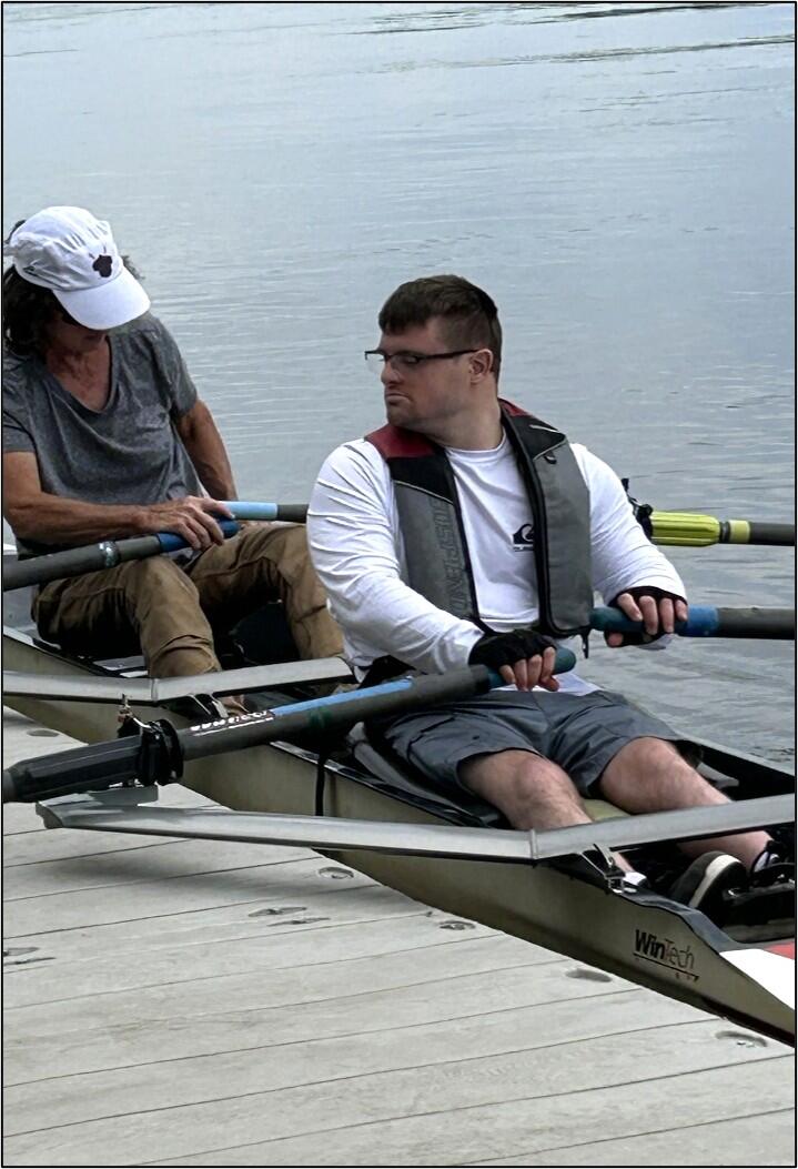 Two people are padding in a canoe on a lake in the woods. 