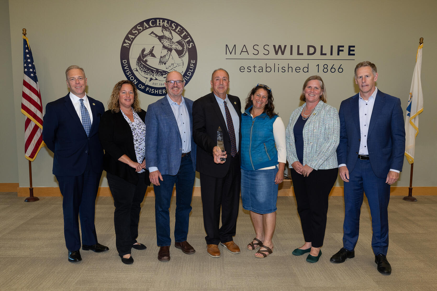 Ernie Foster holds conservation award and stands beside members of the Fisheries and Wildlife Board, MassWildlife Director, and DFG Commissioner.