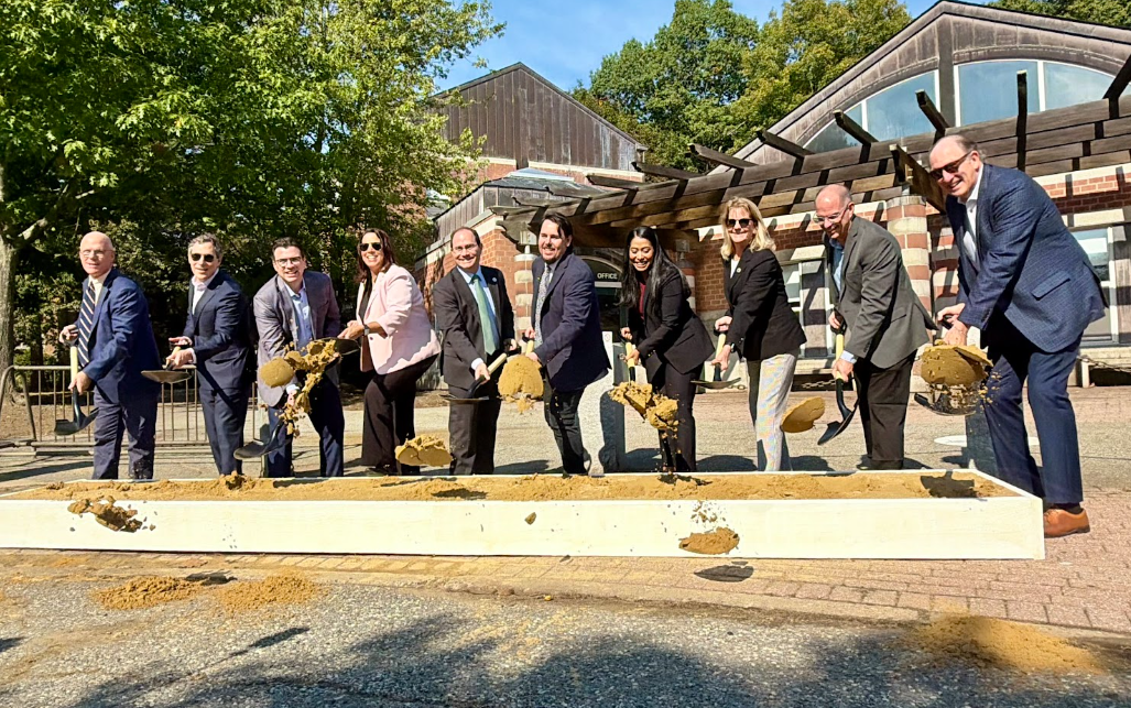Officials pose with shovels behind a pile of dirt