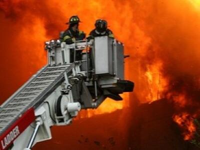 Two firefighters battling fire on ladder truck