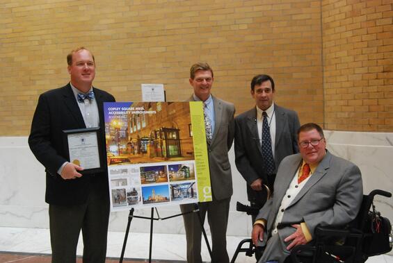 A group of people gathered around the project's display board.