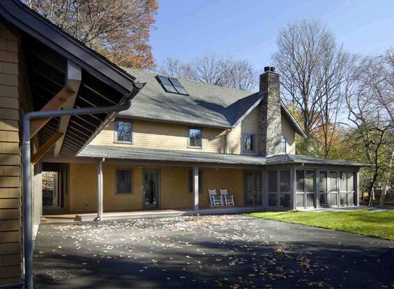 A large suburban home with a wood exterior painted pale yellow and a tiled roof