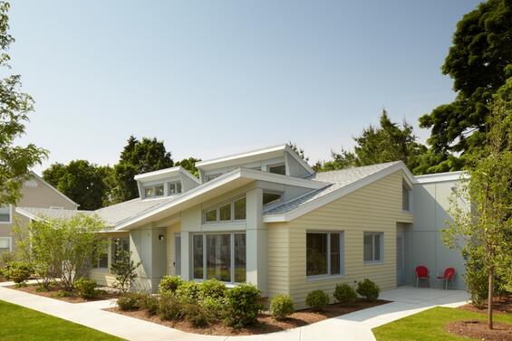 A small one story residential home with pastel yellow walls and a slanted roof.