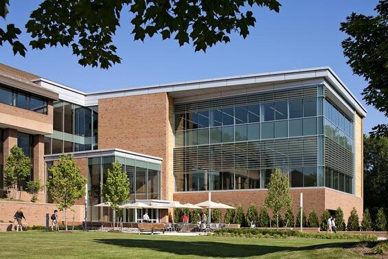 A large brick and glass building behind a plaza.