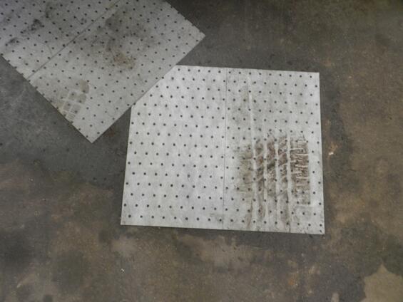 Two white absorbent pads on a cement floor soaking up a spill.