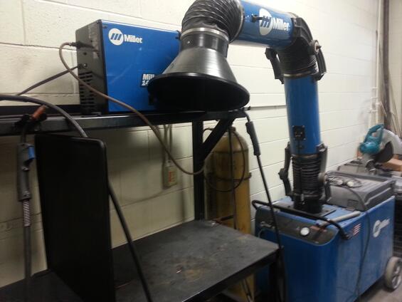 A fume extractor: a black cone connected to a blue tube that extracts fumes from the welding station.