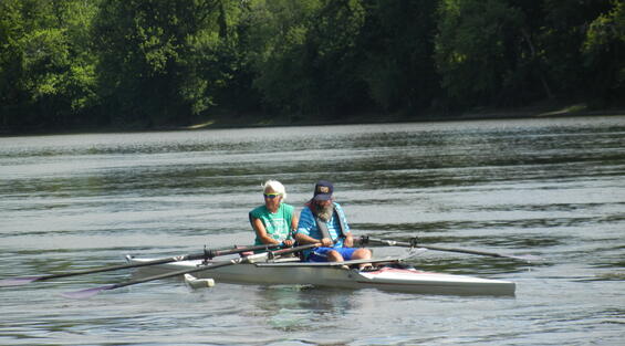 Two people are sculling in a double shell with outriggers on it.