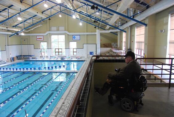 Side view of Tom overlooking an indoor pool from a balcony