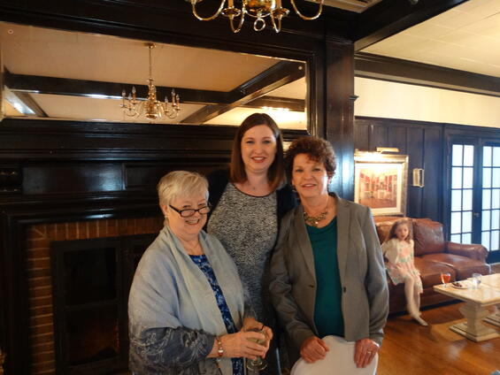 Linda, Kate, and Kathleen stand in front of a fireplace posing for the camera