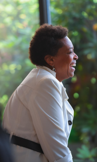 A photograph of a woman with short hair and a white blouse laughing candidly 