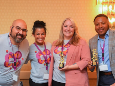 Four people stand side by side smiling at the camera